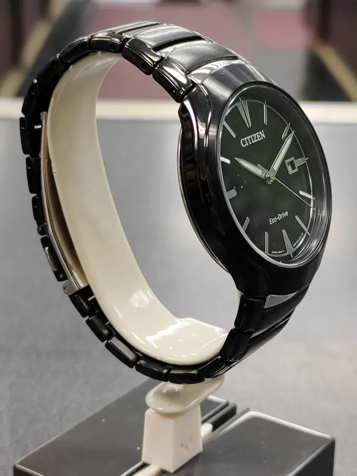 Citizen Eco-Drive black ion-plated stainless steel watch with black dial and date shown from front, side, and ca