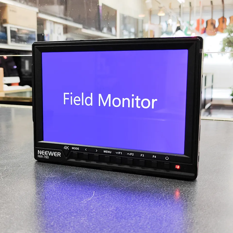 Neewer NW-760 7-inch on-camera field monitor shown powered on, with battery and RavPower dual charger included
