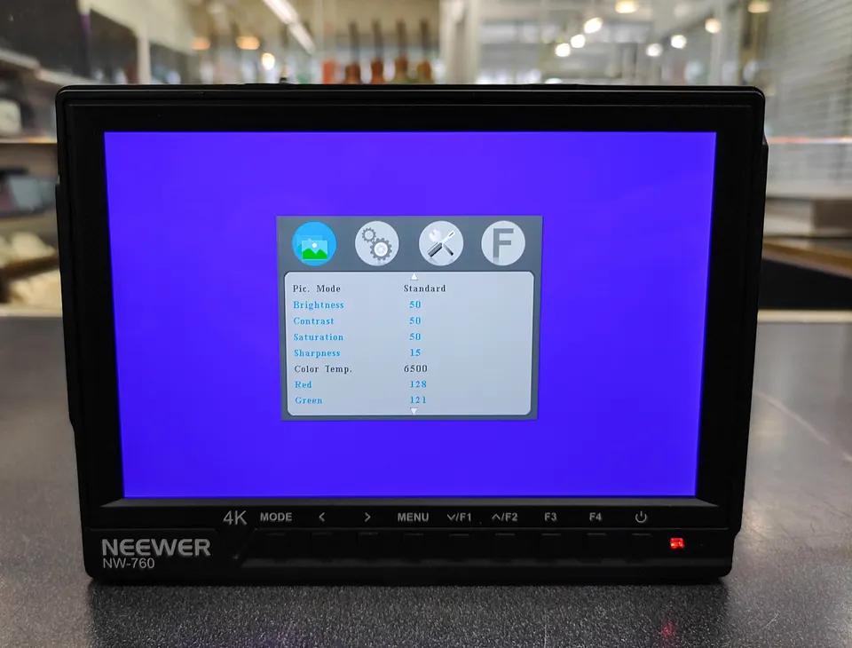 Neewer NW-760 7-inch on-camera field monitor shown powered on, with battery and RavPower dual charger included