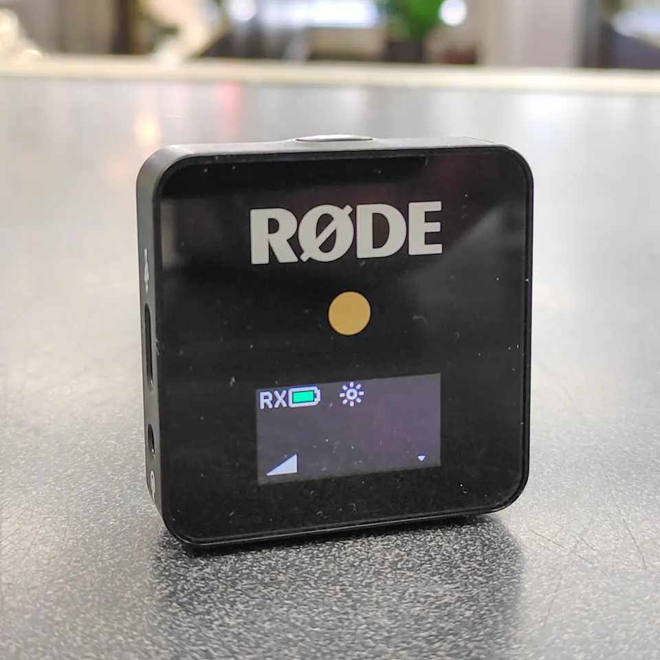 Black RØDE Wireless GO first-generation receiver with built-in clip, display, USB-C charging port, and coiled 3.5mm TRS cable