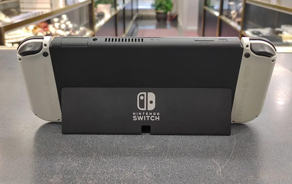 Nintendo Switch OLED White console with dock, Joy-Con controllers, charger, HDMI cable, grip, and wrist straps