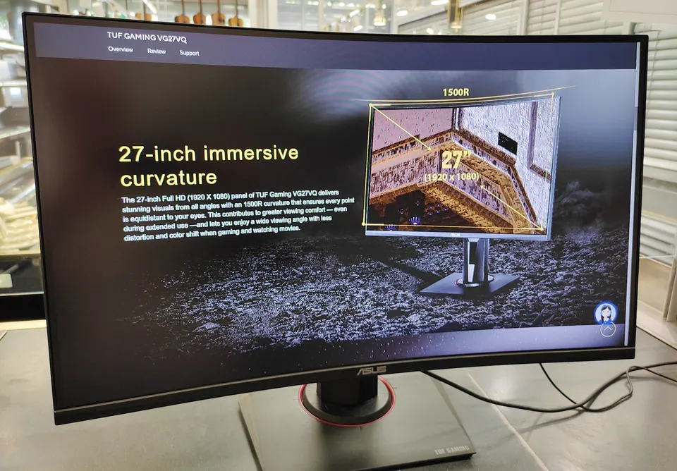 ASUS TUF Gaming VG27VQ 27-inch curved gaming monitor shown powered on with adjustable stand, power adapter, and HDMI cable